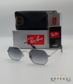 Lunettes de soleil Ray-Ban Octagonal RB3556 argentées avec verres dégradés gris, étui noir, boîte grise et accessoires.